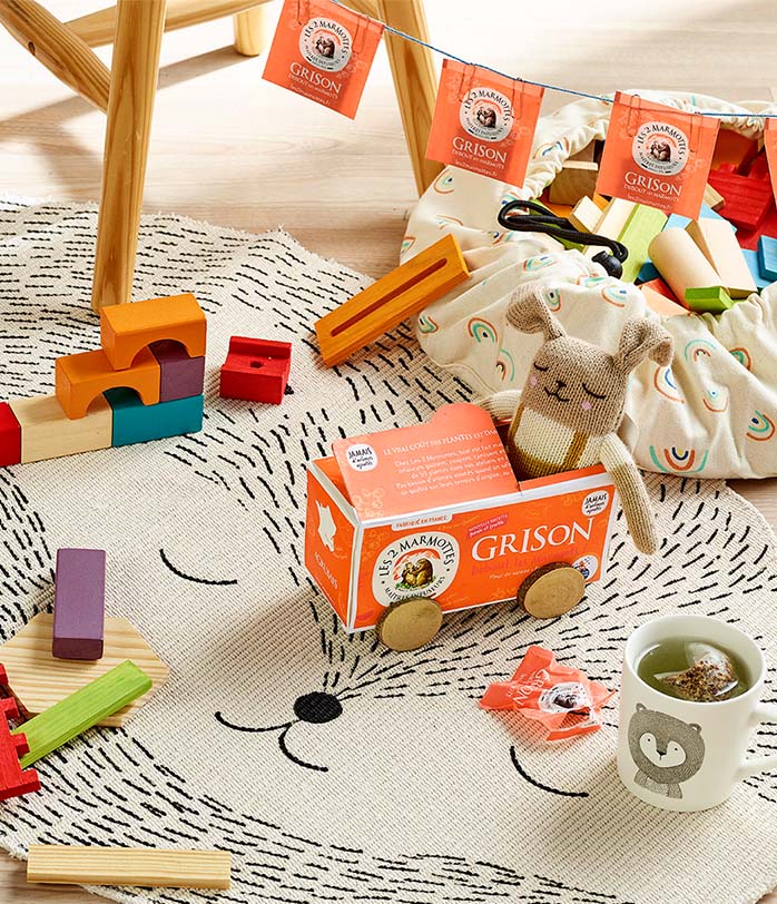 Boîte de Grison debout les Marmots, mise en scène dans chambre d'enfants avec une peluche et une tasse